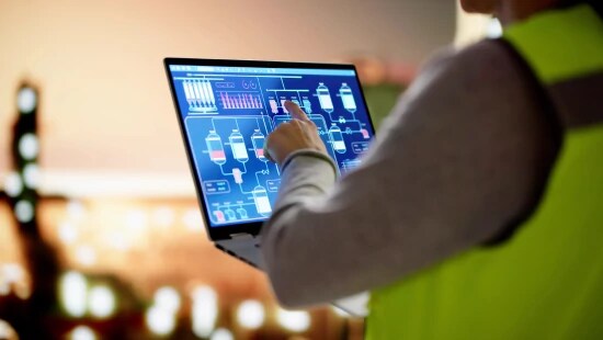 Engineer reviewing screen of laptop with process diagram.